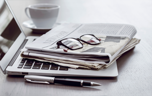 newspaper with glasses on top of a laptop